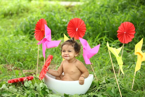 Topless Baby Sitting on White Plastic Bucket