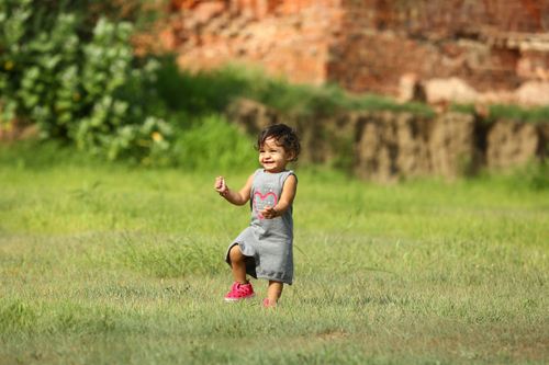 Free A happy child playing on a grassy field, embodying joy and innocence on a bright sunny day. Stock Photo
