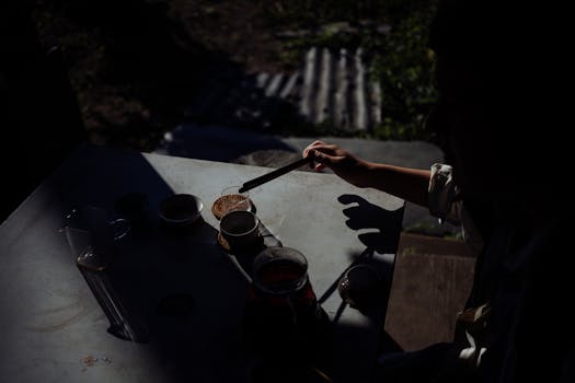 From above of crop unrecognizable person brewing hot aromatic tea into cups during ceremony on terrace at dawn