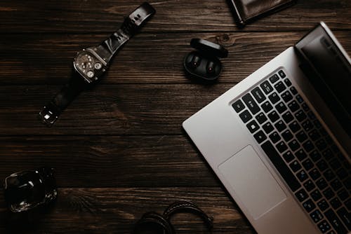 Free Silver and Black Laptop Computer Beside Black Earphones and a Silver Stock Photo