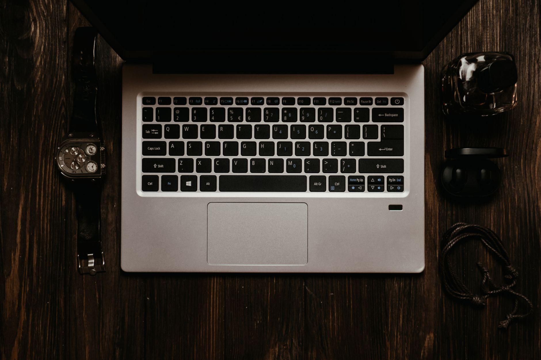 Overhead view of a laptop and tech accessories on a wooden desk. Modern still life.