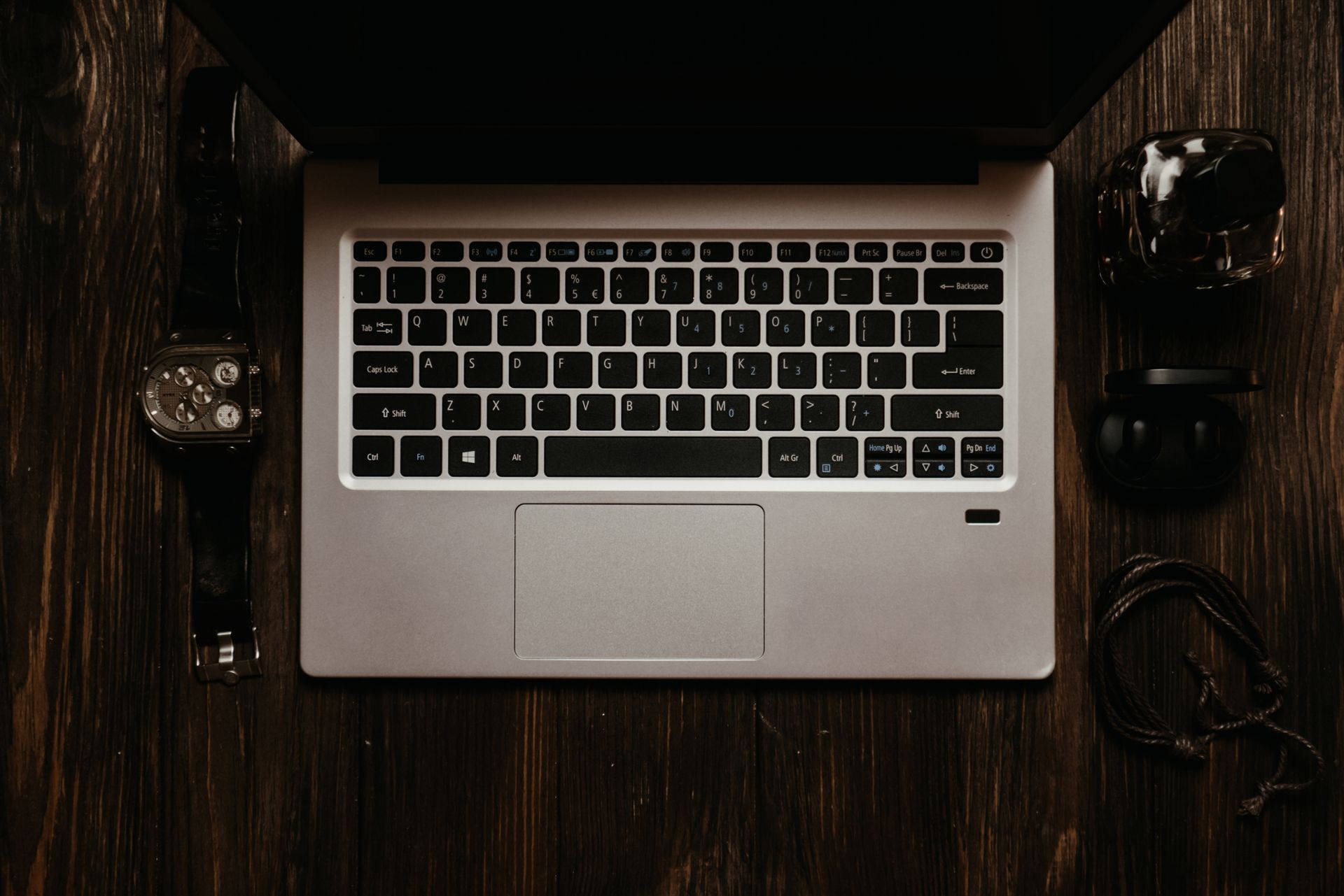 Overhead view of a laptop and tech accessories on a wooden desk. Modern still life.