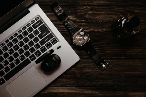 Chromed Watch with Laptop and Earphones on a Wooden Surface