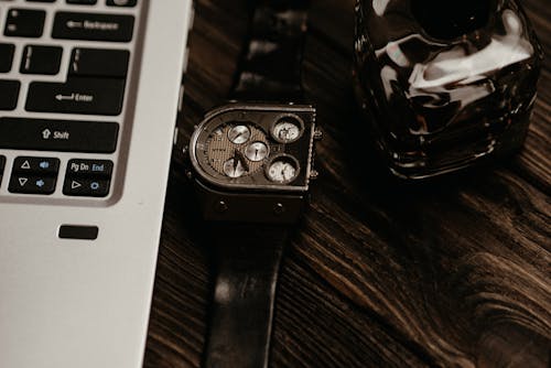 Silver Chronograph Watch with a Laptop on a Wooden Surface