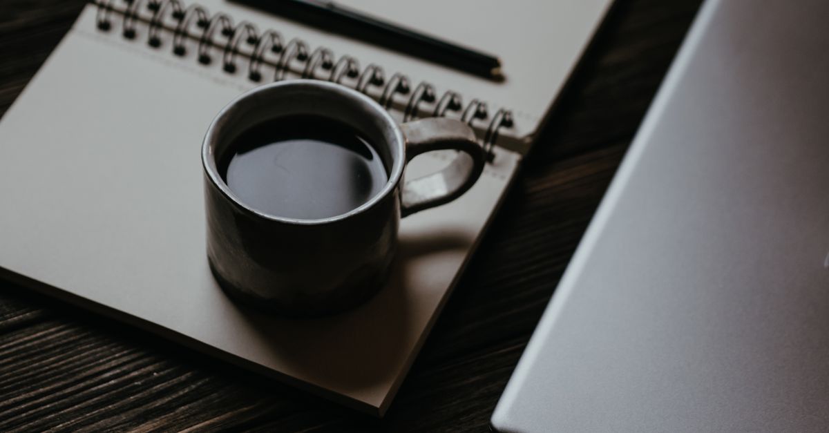 A writer’s desk with a laptop, coffee, and notes, conveying creativity and focus
