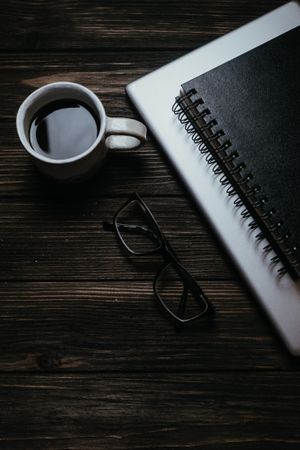 Coffee, notebook and glasses on a dark desk — Polina on Pexels