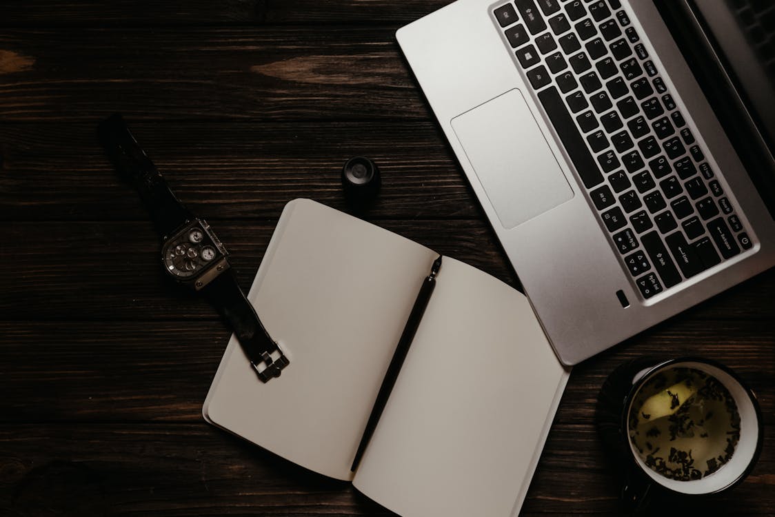 An Open Notebook Beside the Laptop · Free Stock Photo