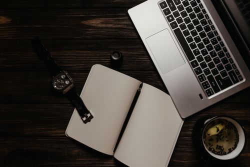 Free Flat lay of a productive workspace featuring a laptop, notebook, and a calming cup of tea. Stock Photo