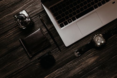 Free Wristwatch and Laptop Near a Perfume Bottle and Wallet Stock Photo