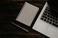 Notepad and a Laptop on Wooden Table