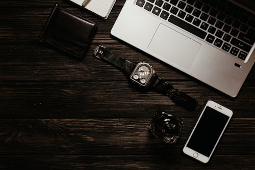 A Wristwatch and a Smartphone Near a Laptop
