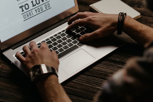 Pessoa Usando O Macbook Pro Em Uma Mesa De Madeira Marrom