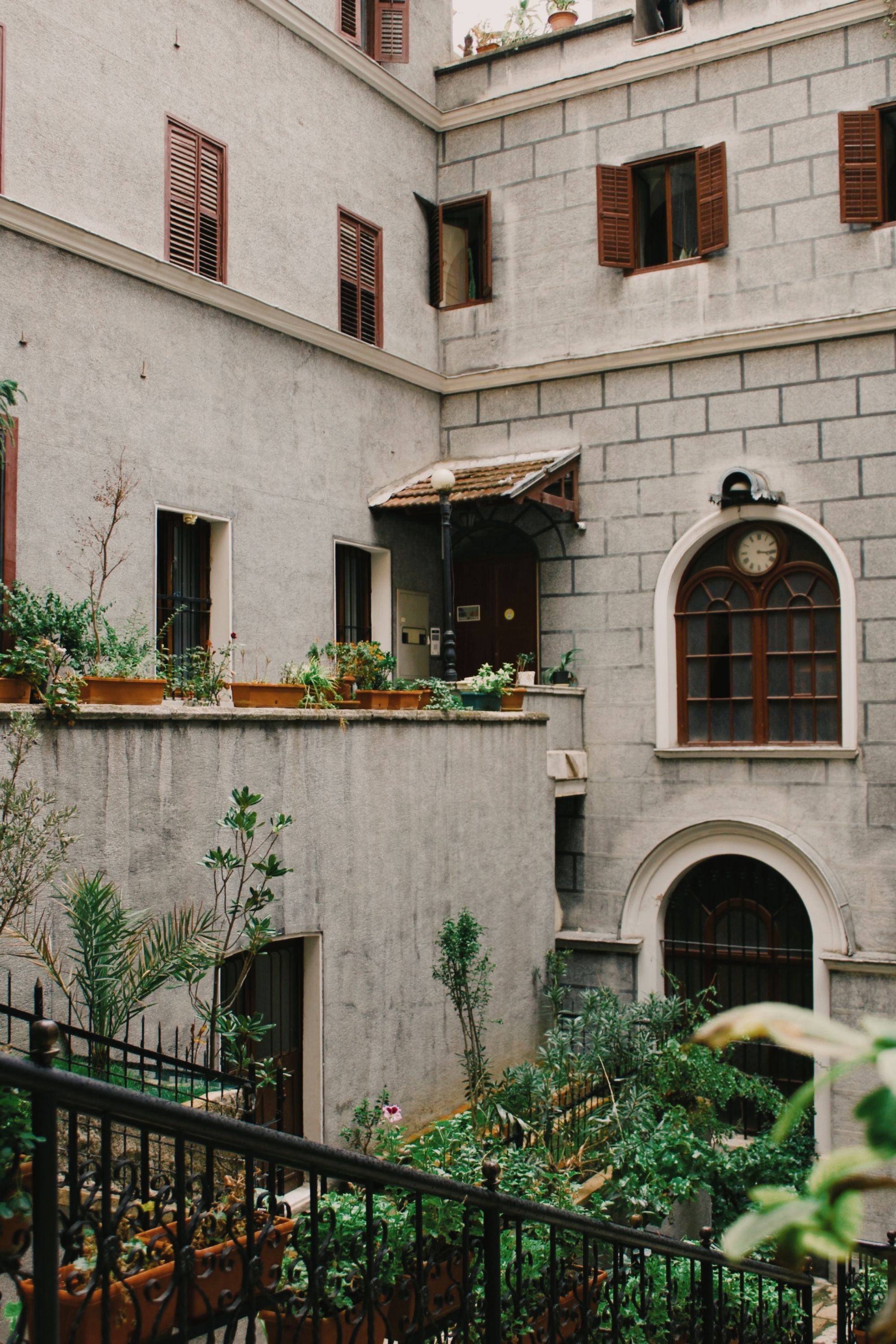 Cozy courtyard with lush plants and historic tenement architecture.