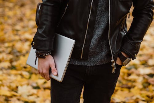 Free Person in Black Leather Jacket Holding a Laptop Stock Photo