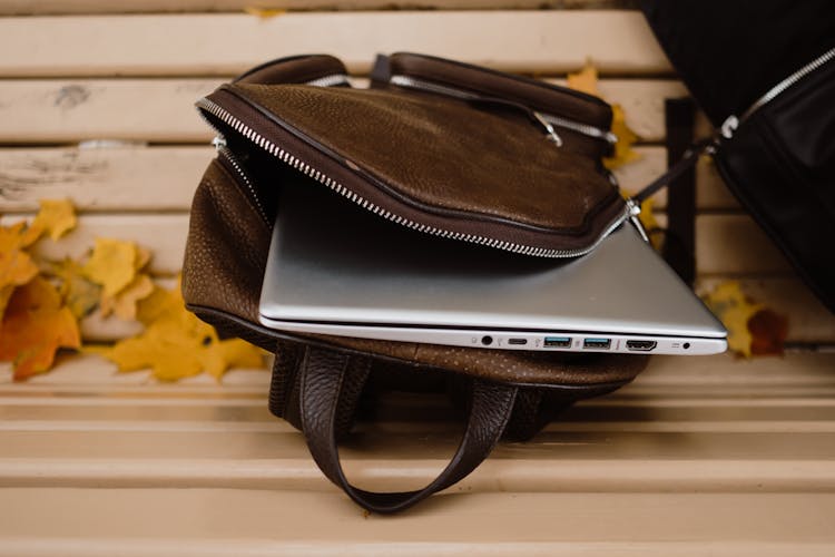 A Silver Laptop Inside The Brown Leather Bag 