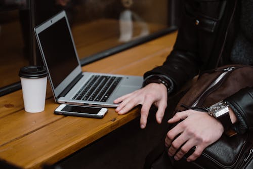 Persona Che Utilizza Macbook Pro Sulla Tavola Di Legno Marrone