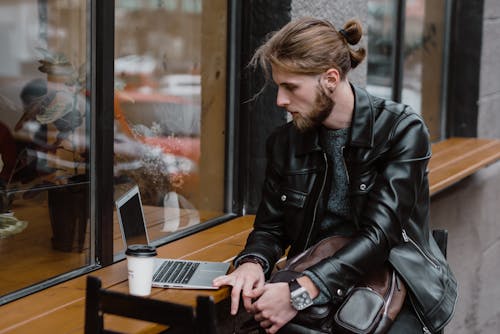 A Bearded Man Using a Laptop on a Wooden Table