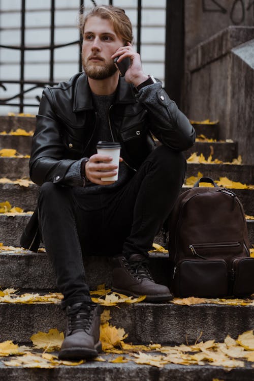 A Man Sitting on a Concrete Stairs Holding a Disposable Cup