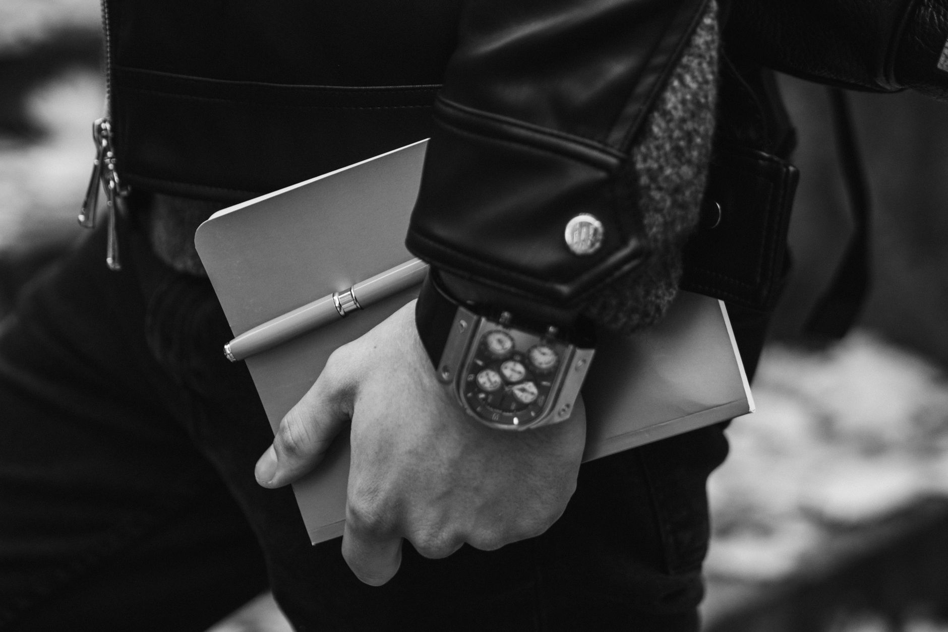 A person in leather jacket holding notebook and pen, highlighting style and productivity.
