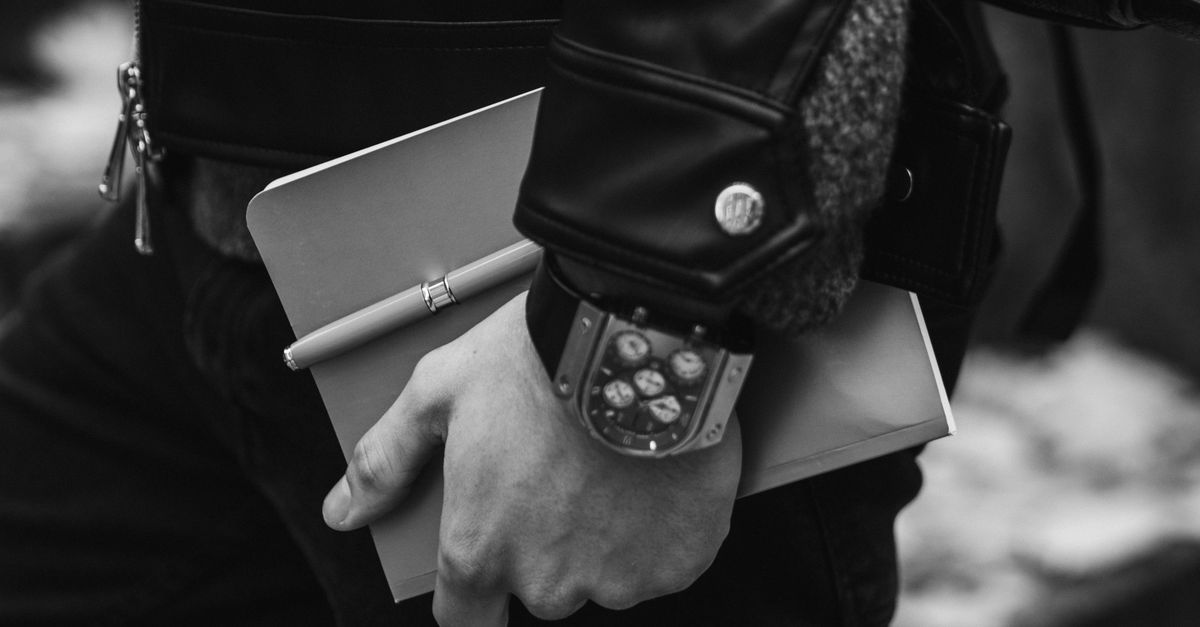 Close-up of an athlete’s hand writing in a black journal, with a stopwatch nearby
