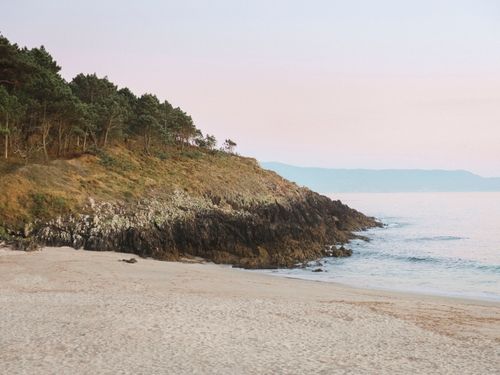 Free Peaceful morning beach scene with cliffs and sea at Cangas, Spain. Stock Photo