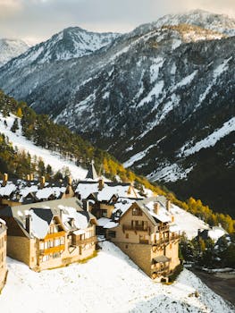 Snow-covered village nestled in the Pyrenees, captured in winter from above.