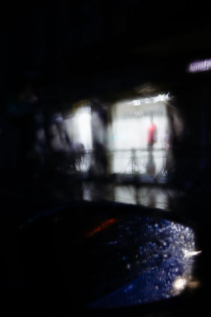 Through car window of unrecognizable pedestrian walking on city street at rainy night