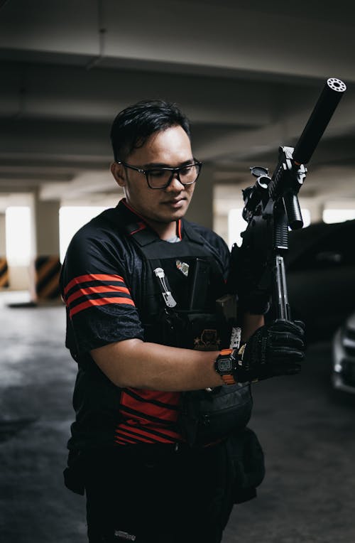Man in Black and Red Polo Shirt Holding Black Rifle
