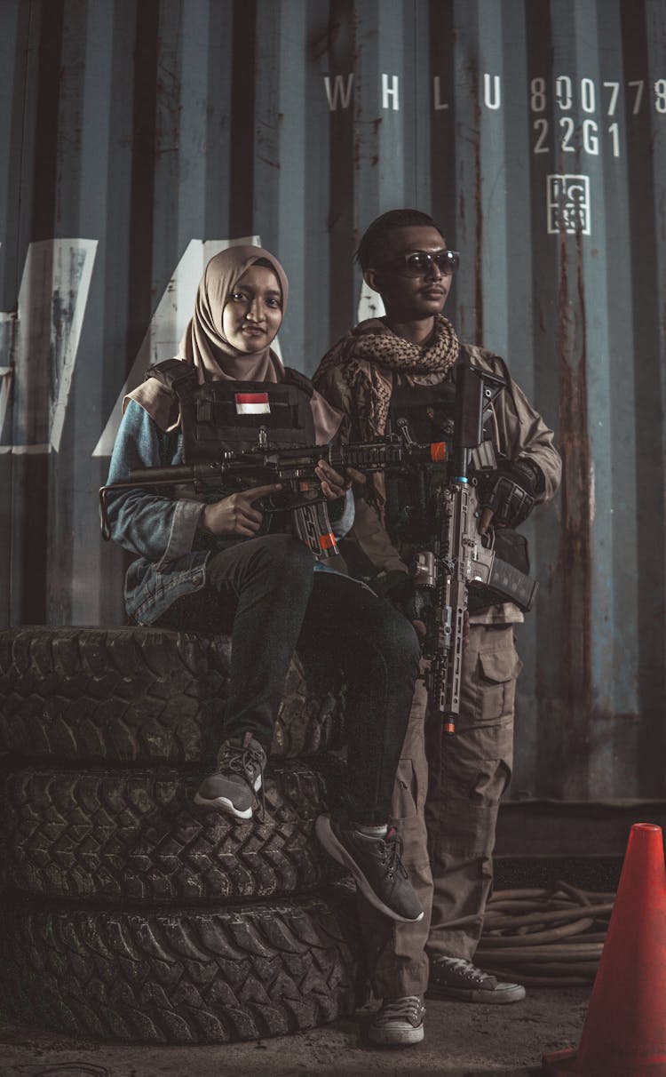 Woman And Man In Military Uniforms Holding Machine Guns 