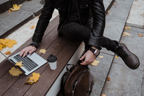 Free A person working on a laptop outdoors during autumn, surrounded by fallen leaves. Stock Photo