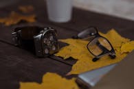 A Wristwatch and Eyeglasses on the Wooden Table