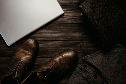 棕色皮鞋、笔记本电脑和木地板上的服装顶视图，营造出精致的商务外观