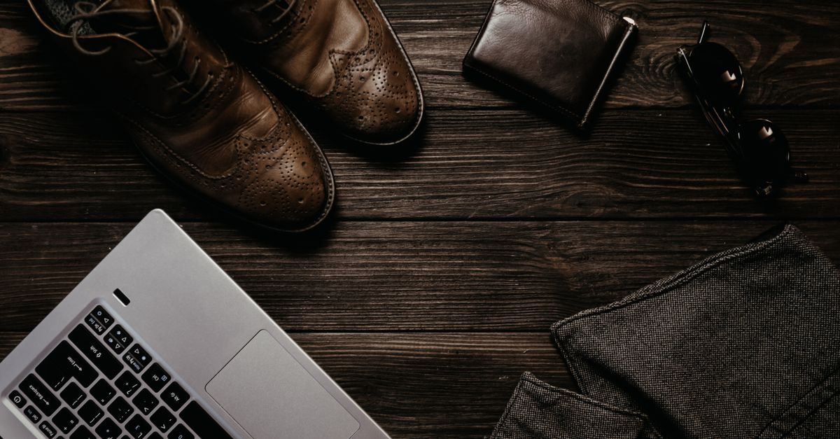 A flat lay of a wardrobe capsule featuring a navy blazer, cream trousers, a white tee, and leather loafers