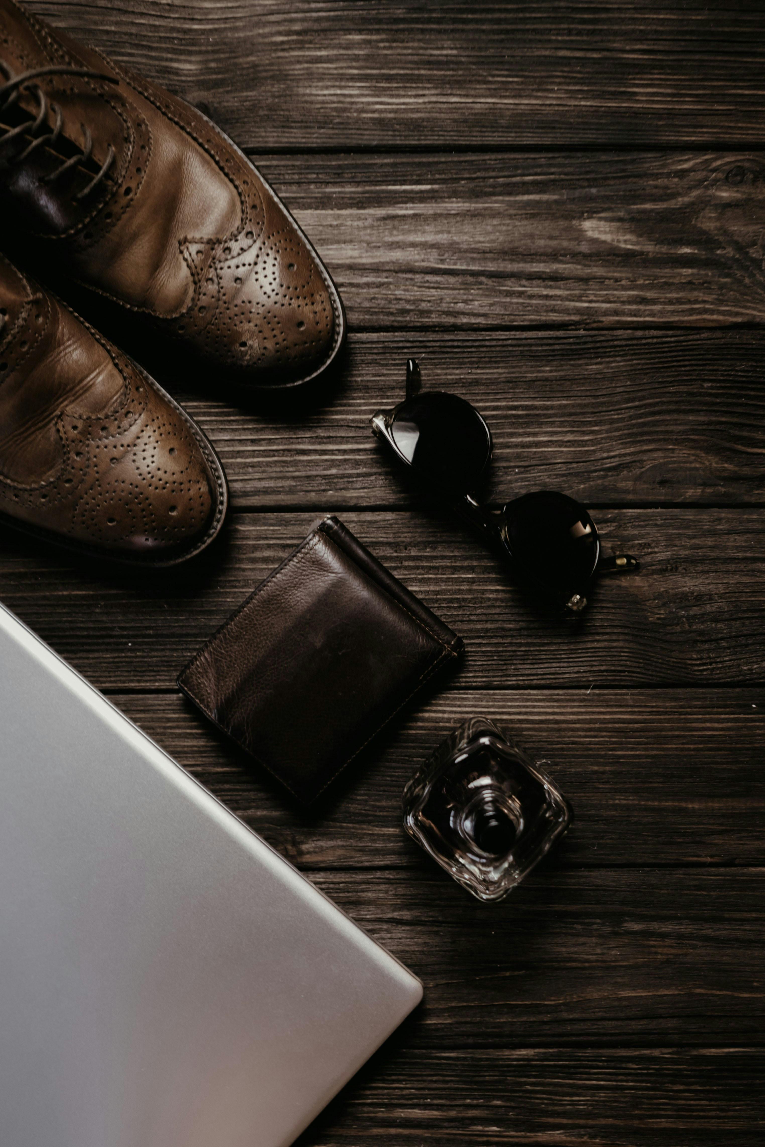 a leather wallet and sunglasses on the wooden surface