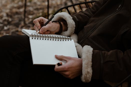 A man in a cozy jacket writing in a notebook outdoors during fall. Perfect for creative and freelance themes.