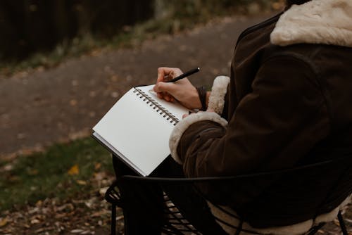 Personne En Manteau Brun Tenant Un Livre Blanc