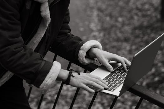 A person using a laptop outdoors in fall, reflecting freelance lifestyle and work flexibility.