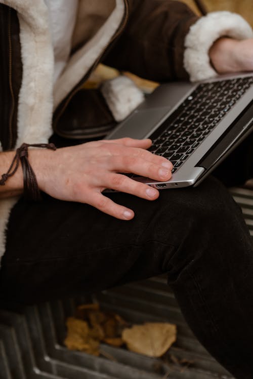 A Person in Black Long Jacket Using a Laptop