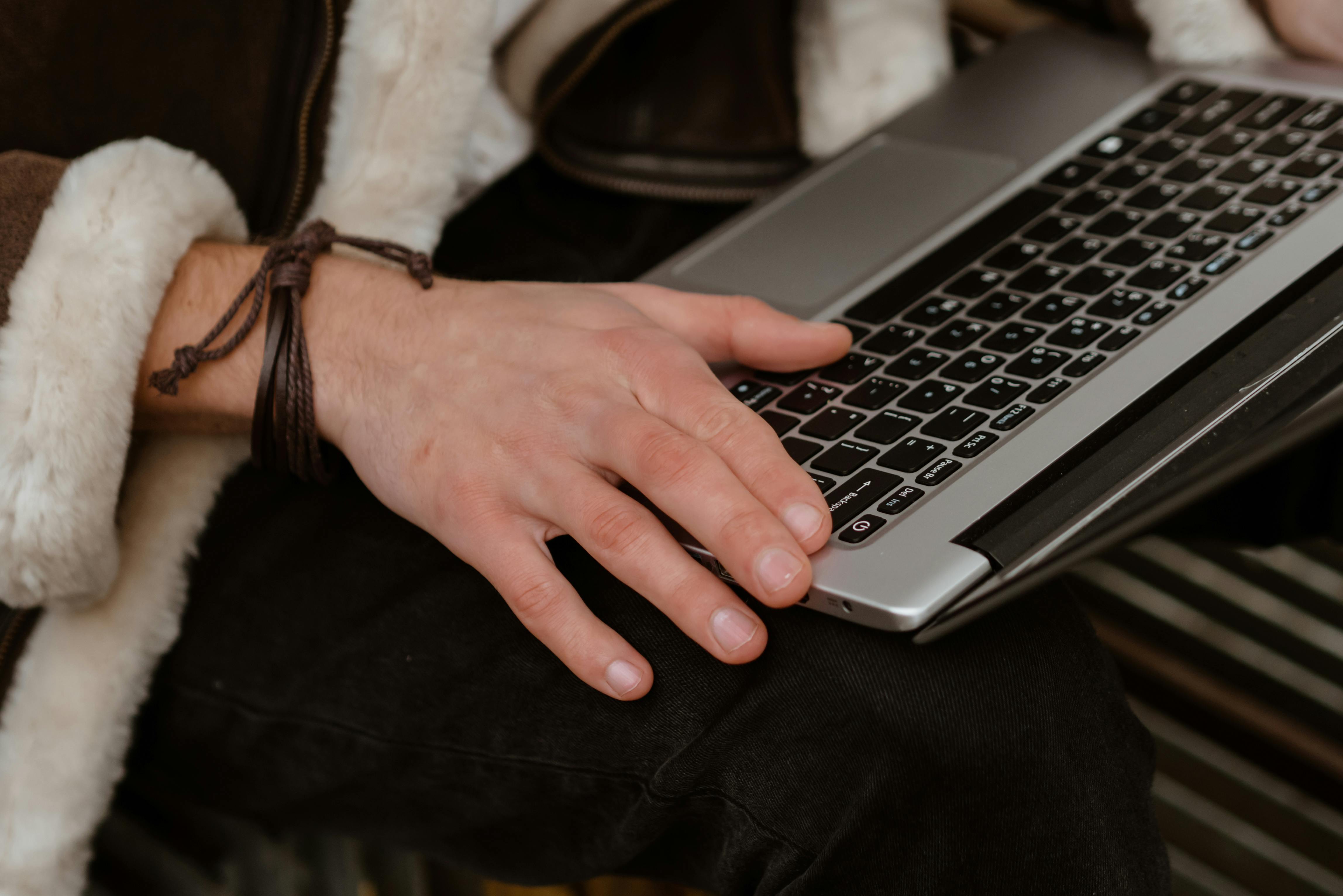 person using macbook pro on black textile