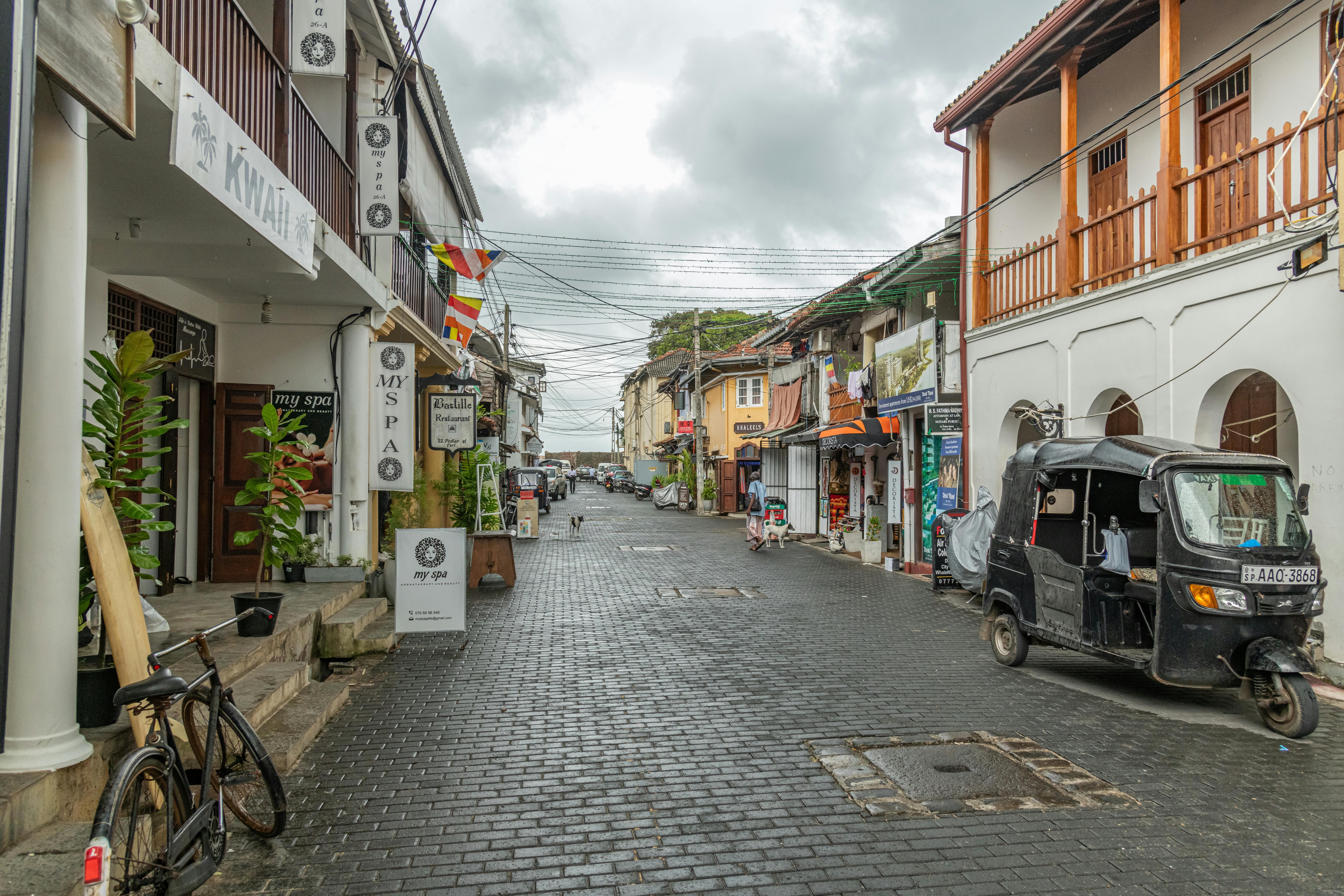 Scenic view of a cobblestone street with a black tuk-tuk in urban setting. - ¿Cómo alquilar un tuk-tuk en Sri Lanka?