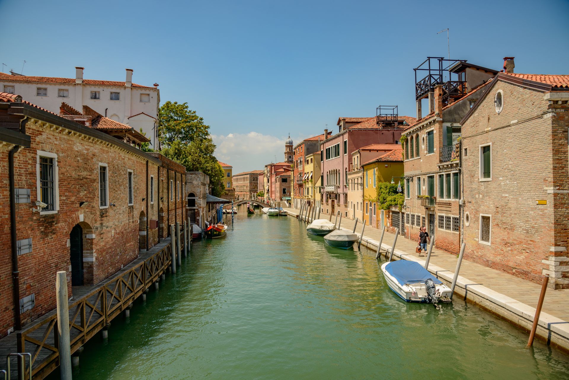 Charming Venetian canal with colorful townhouses and boats on a sunny day.