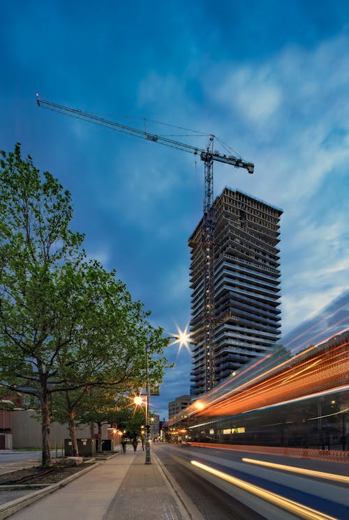 Green Trees Beside Concrete Building With a Crane