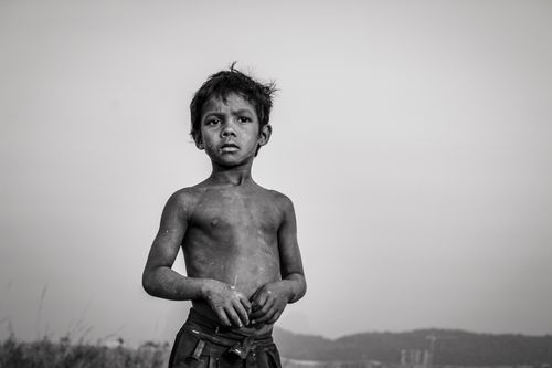 Free Black and white image of a young boy outdoors, evoking themes of poverty and resilience. Stock Photo