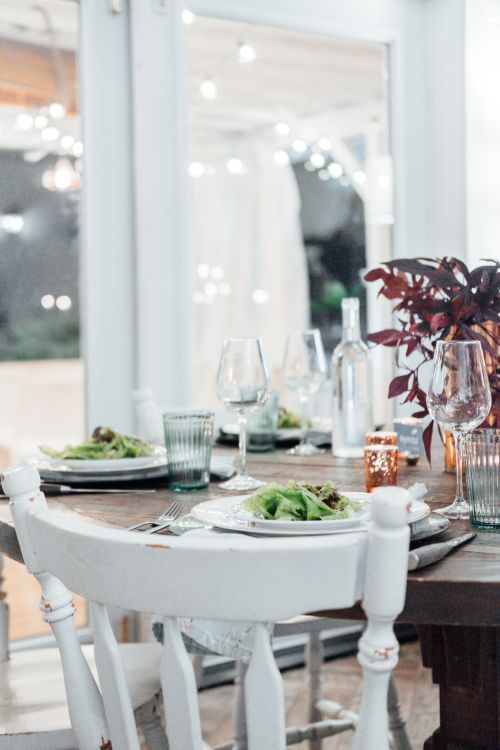 Free Beautifully set dinner table in a cozy restaurant with wine glasses and a decorative plant centerpiece. Stock Photo