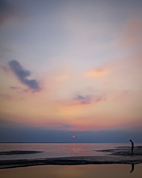 Free A Person Standing on Beach during Sunset Stock Photo