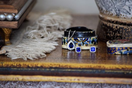 Close-up of elegant jewelry including earrings and pendant on a rustic table setting.