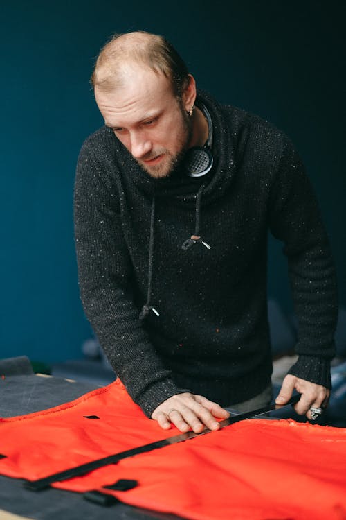 Focused male tailor working with piece of cloth in workshop