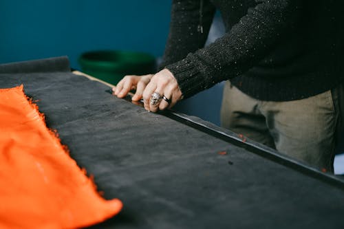 Person in Black Long Sleeve Shirt Holding a Ruler on a Black Fabric