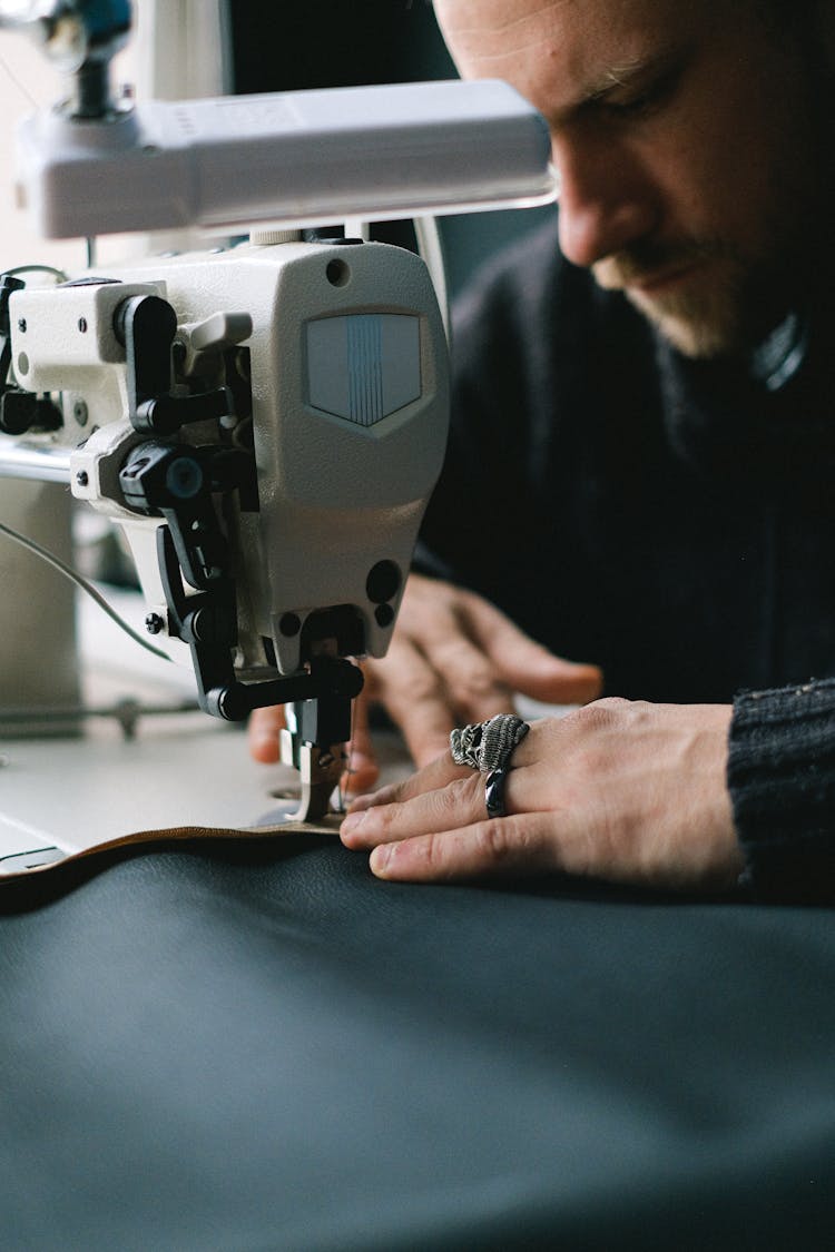 A Man Sewing A Blue Fabric