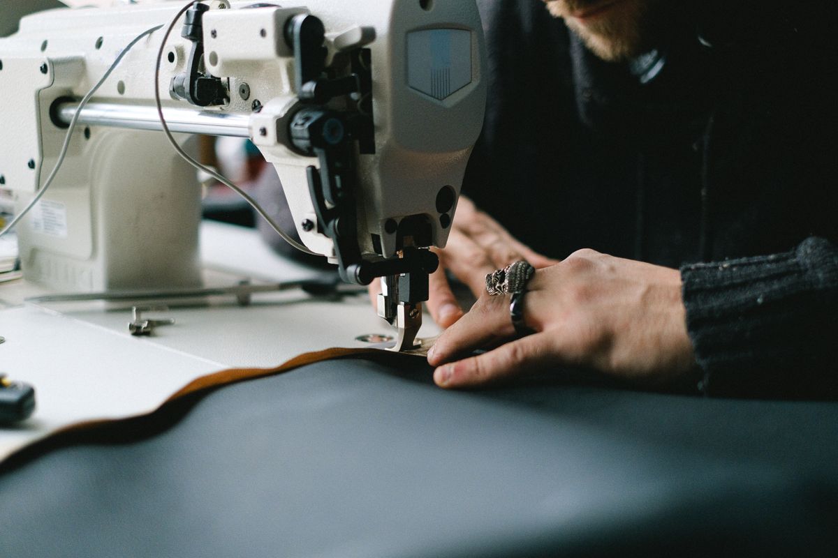 Hands at an industrial sewing machine during a garment repair